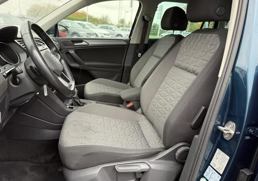 Vue intérieure côté conducteur du Volkswagen Tiguan 2022 bleu nuit, sièges tissu gris à motifs géométriques.