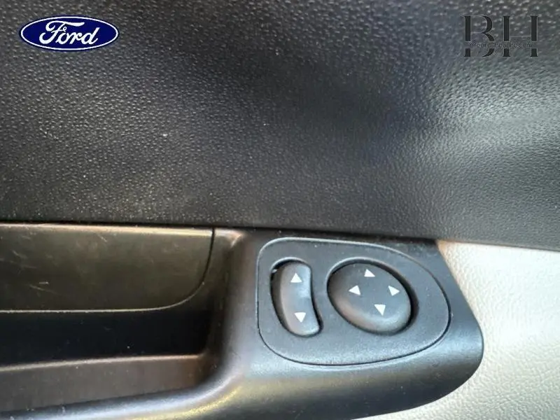 Gros plan sur les commandes de réglage des rétroviseurs côté gauche de la porte intérieure d'une Fiat 500 blanche.