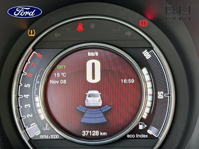 Vue rapprochée du tableau de bord numérique de la Fiat 500 blanche, affichant la vitesse et le radar de recul actif.