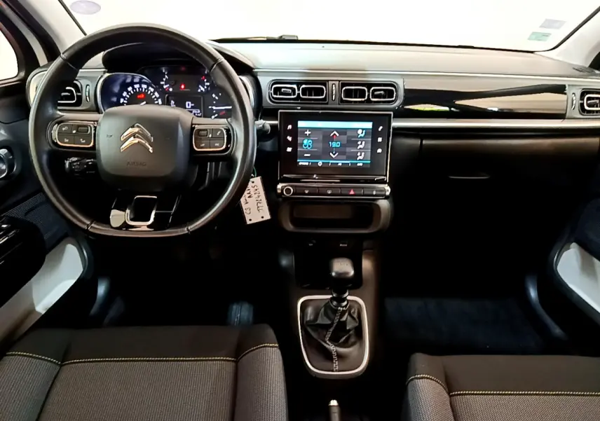 Vue intérieure avant de la Citroën C3 blanche 2019, tableau de bord noir avec écran tactile et volant cuir multifonctions.