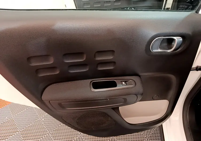 Vue rapprochée de la porte avant droite blanche de la Citroën C3 avec panneau noir et poignée argentée.