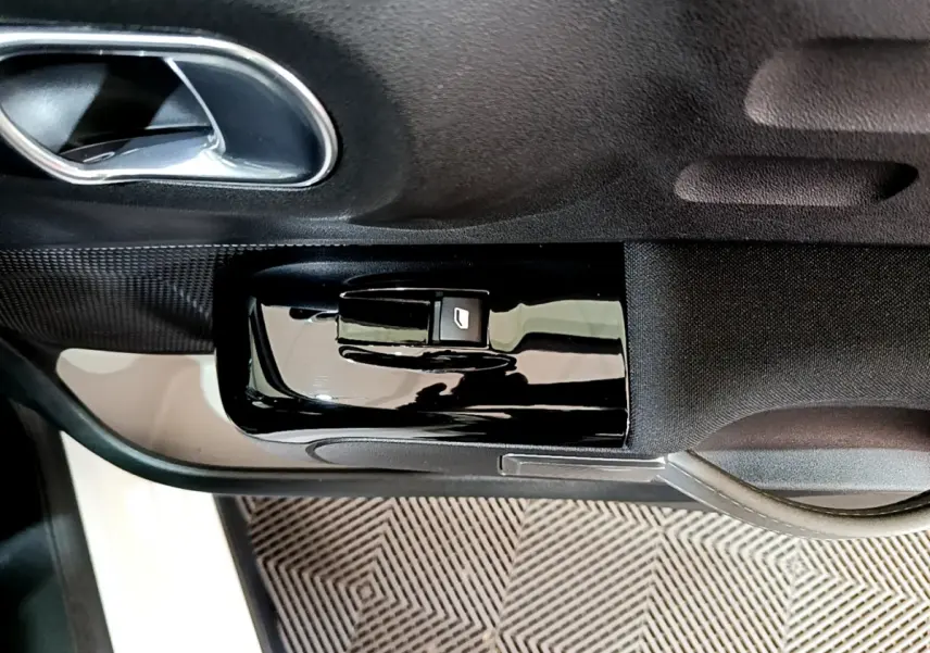Gros plan sur la commande de lève-vitre côté conducteur noir brillant dans la portière intérieure d'une Citroën C3 blanche de 2019.