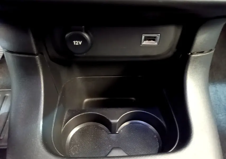 Gros plan sur la console centrale noire de la Citroën C3 2019 avec prise 12V et port USB au-dessus des porte-gobelets.