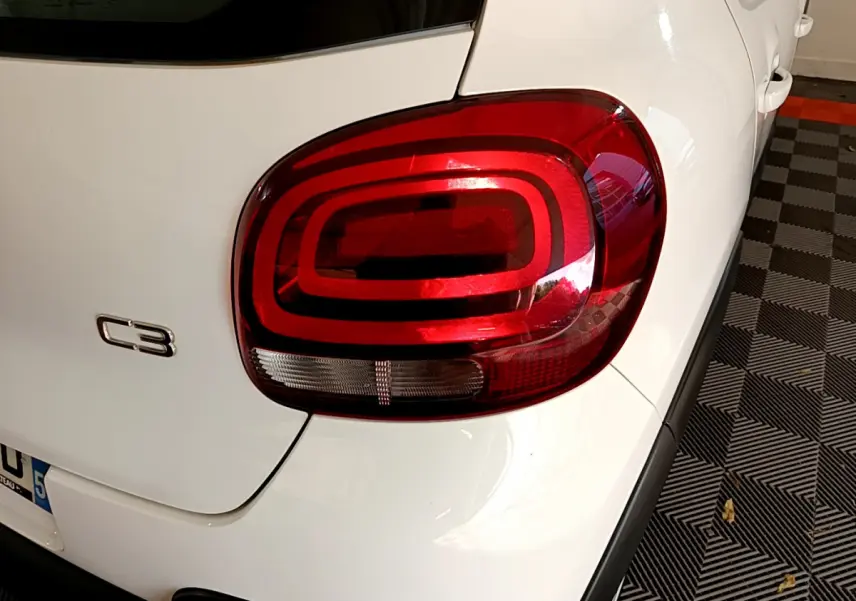 Gros plan sur le feu arrière droit rouge d'une Citroën C3 blanche de 2019, avec logo C3 visible sur le coffre.