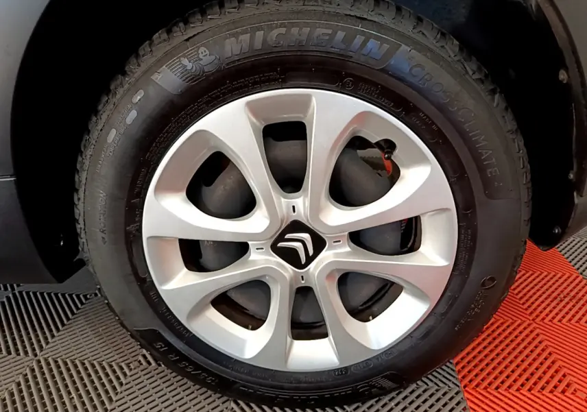 Gros plan sur la roue avant droite d'une Citroën C3 blanche avec jante alliage et pneu Michelin CrossClimate.