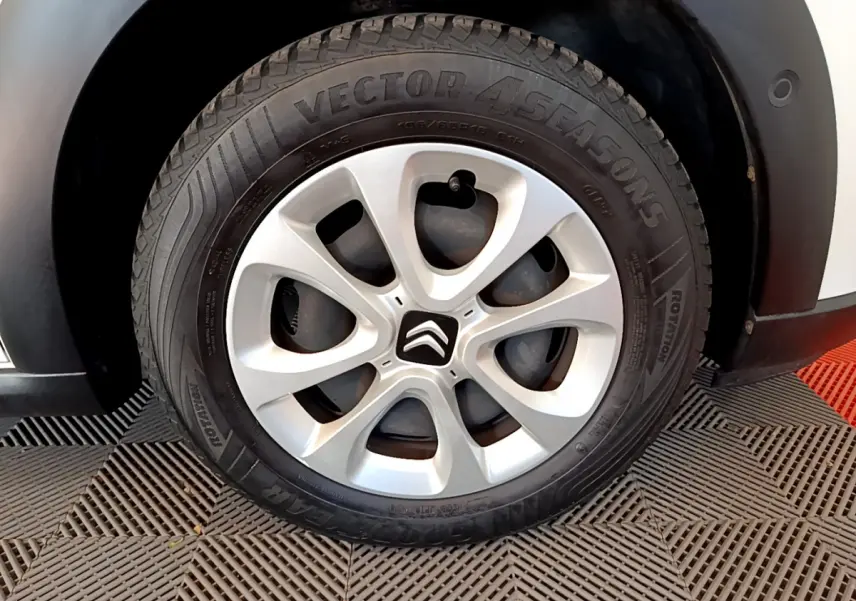 Gros plan sur la roue avant droite d'une Citroën C3 blanche, jante alliage argentée avec logo Citroën central.