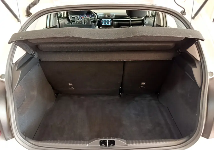 Coffre ouvert d'une Citroën C3 blanche, vue arrière montrant l'intérieur noir et le tableau de bord tactile.