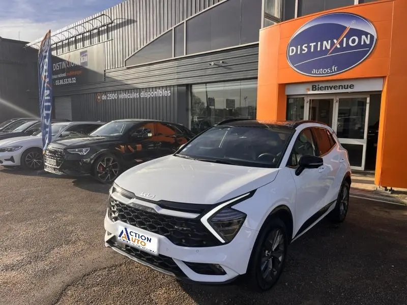 KIA Sportage blanc nacré en vue 3/4 avant droit, avec toit noir et calandre au design hexagonal marqué.