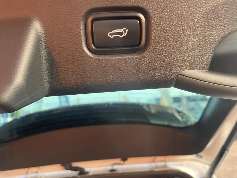 Bouton d'ouverture électrique du coffre sur le hayon intérieur d'un Kia Sportage blanc nacré 2022.