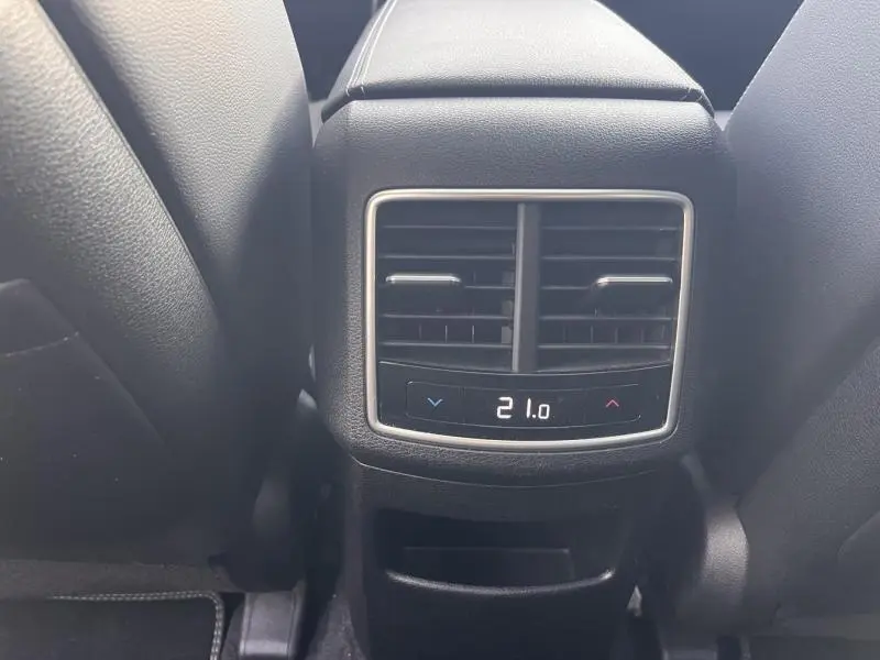 Détail de la console arrière noire avec réglage numérique de la climatisation à 21°C dans un Kia Sportage blanc nacré.