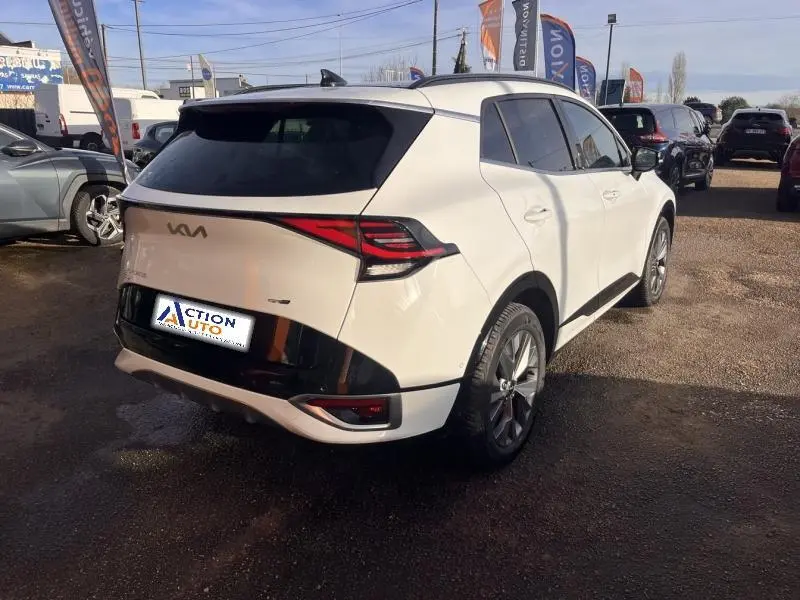 Vue 3/4 arrière droite d'un KIA Sportage blanc nacré avec feux arrière LED et toit noir contrasté.