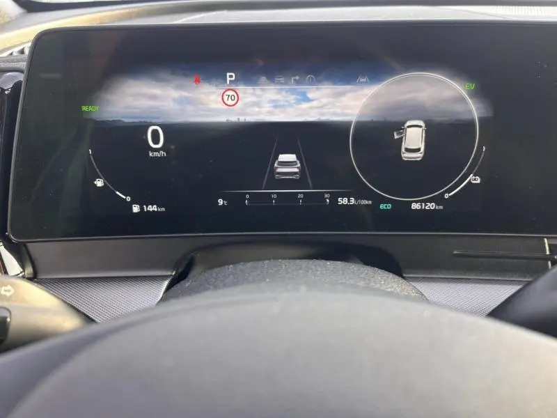Vue du tableau de bord numérique du Kia Sportage blanc nacré 2022, affichant la vitesse à 0 km/h et l'assistance à la conduite active.