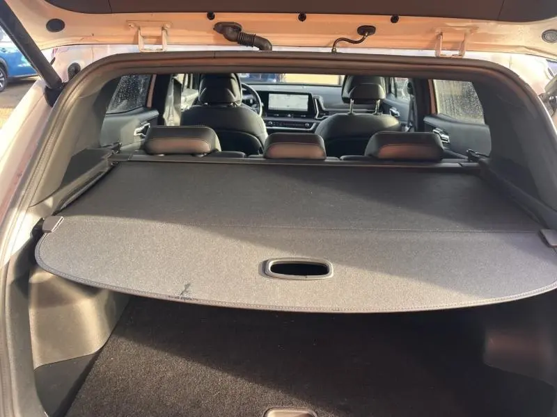 Vue arrière du coffre du Kia Sportage blanc nacré 2022, avec cache-bagages déployé et intérieur cuir noir visible.