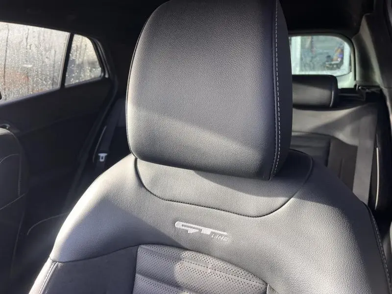 Gros plan sur l'appui-tête en cuir noir avec logo GT-Line du siège avant du Kia Sportage blanc nacré 2022.