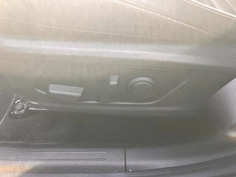 Détail des commandes électriques du siège conducteur du Kia Sportage blanc Sensation nacré 2022, côté gauche.