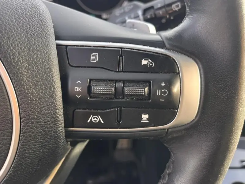 Gros plan sur les commandes de régulateur de vitesse et d'assistance au volant du KIA Sportage blanc nacré 2022, côté droit du volant.