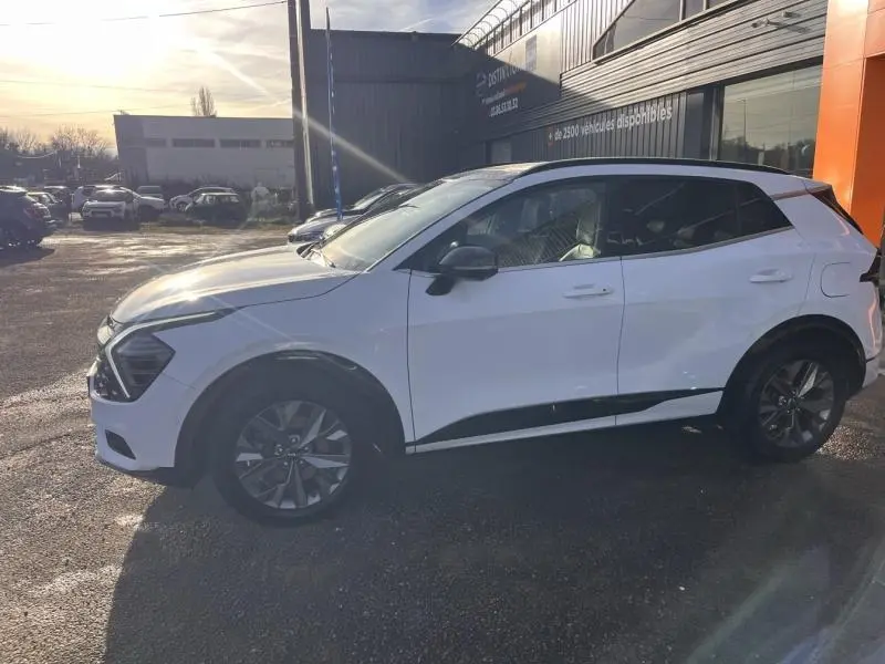 Vue de profil côté gauche d'un KIA SPORTAGE blanc nacré avec jantes alliage et détails noirs contrastants.