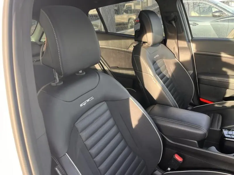 Vue intérieure des sièges avant noirs GT-Line avec surpiqûres blanches du KIA Sportage 2022, côté gauche.