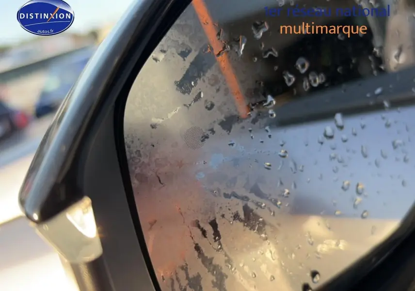 Rétroviseur côté gauche d’un Peugeot 3008 gris 2025 avec gouttes d’eau et clignotant intégré allumé.