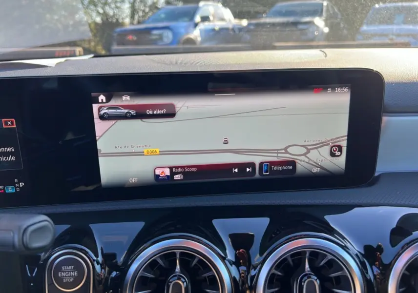 Vue intérieure du tableau de bord de la Mercedes Classe A 200D Exclusive Design avec écran tactile GPS et aérateurs ronds noirs brillants.