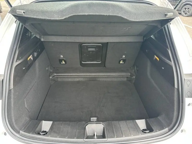Coffre ouvert vu de l’arrière d’un Alfa Romeo Tonale blanc Monterosa Pastel, espace de chargement vide et tapis noir.
