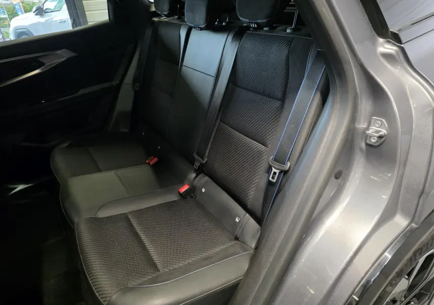 Vue intérieure côté droit sur la banquette arrière mixte tissu et Alcantara noire avec surpiqûres bleues du Renault Austral gris foncé.