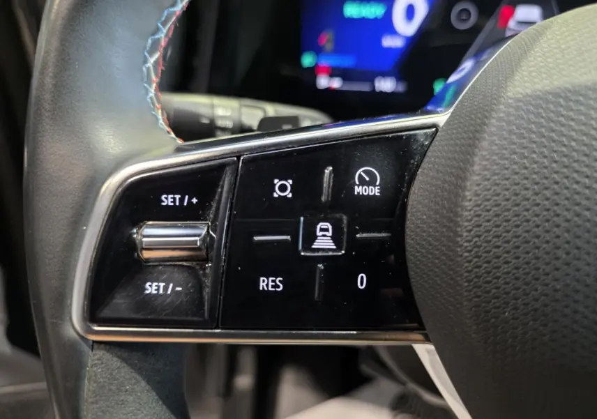 Gros plan sur les commandes gauche du volant textile avec insert Alcantara du Renault Austral gris foncé 2024.