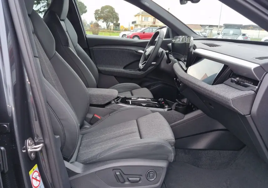 Intérieur côté conducteur de l'Audi Q6 e-tron Performance S-Line 2025 en gris Manhattan, sièges sport et tableau de bord moderne.