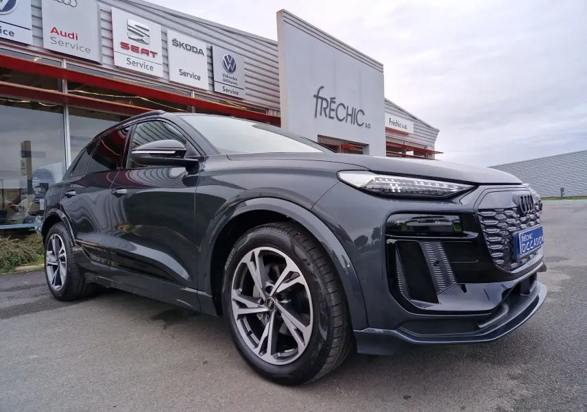 Audi Q6 e-tron Performance S-Line gris Manhattan en 3/4 avant droit, avec jantes Audi Sport et pack esthétique noir.