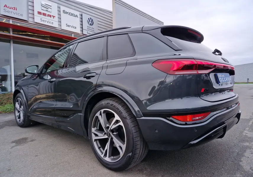 Vue 3/4 arrière droite d'un Audi Q6 e-tron Performance S-Line gris Manhattan avec jantes Audi Sport et feux LED.