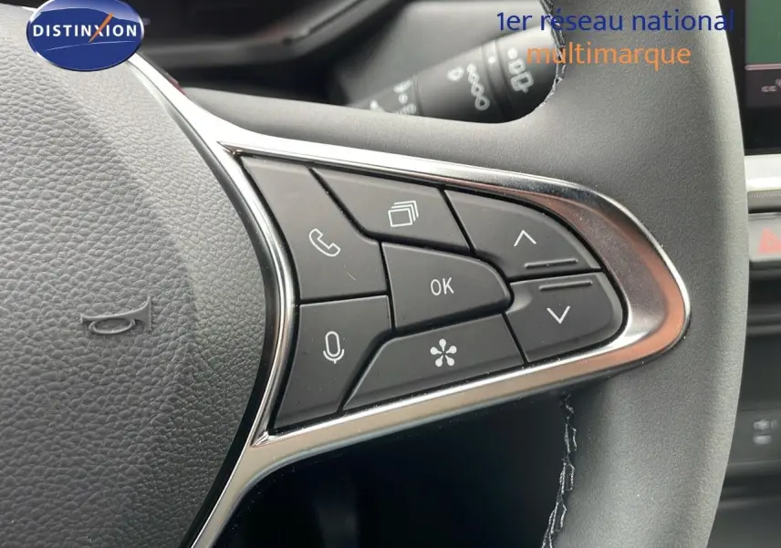 Gros plan sur les commandes multifonctions à droite du volant du Renault Captur gris Rafale 2025 avec finition beige.