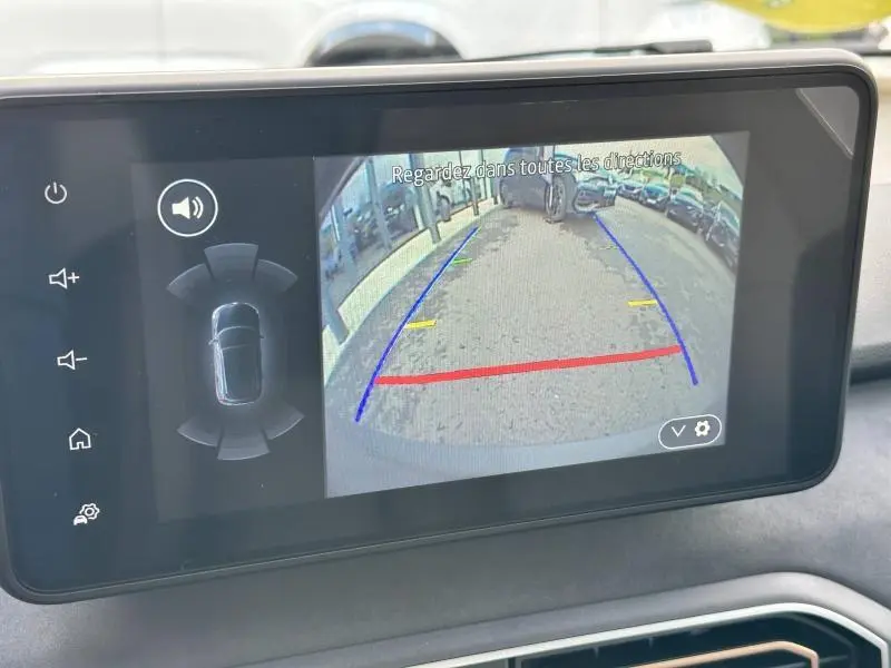 Écran central du DACIA Sandero Stepway 2025 montrant la caméra de recul avec guidage coloré sur un parking.