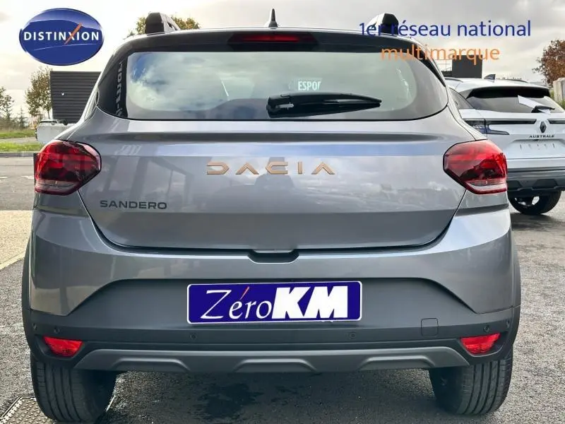 Vue arrière d'une Dacia Sandero Stepway 2025 en gris schiste métallisé avec logo Dacia en relief cuivré.