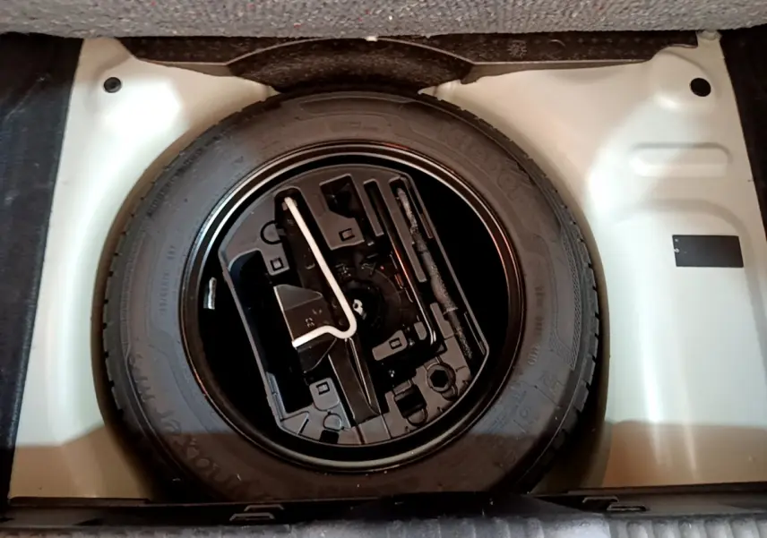 Gros plan sur la roue de secours noire dans le coffre blanc d'une Citroën C3 PureTech 110 Essence 2019