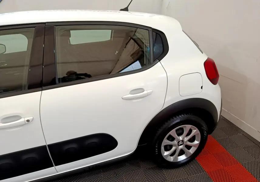 Vue latérale côté droit d'une Citroën C3 blanche avec protections noires sur les portières et jantes argentées.