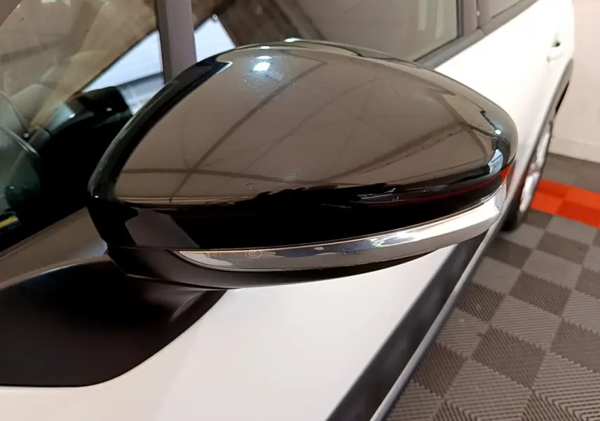 Gros plan sur le rétroviseur droit noir brillant d'une Citroën C3 blanche vue de côté, avec clignotant intégré.