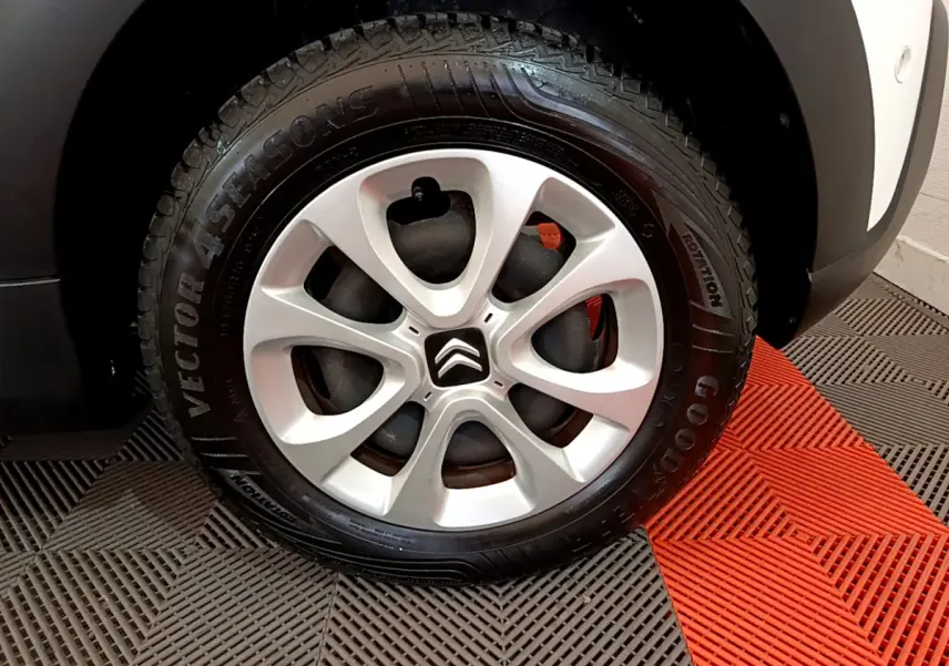 Gros plan sur la roue avant droite d'une Citroën C3 blanche, mettant en valeur la jante alliage et le pneu Goodyear.