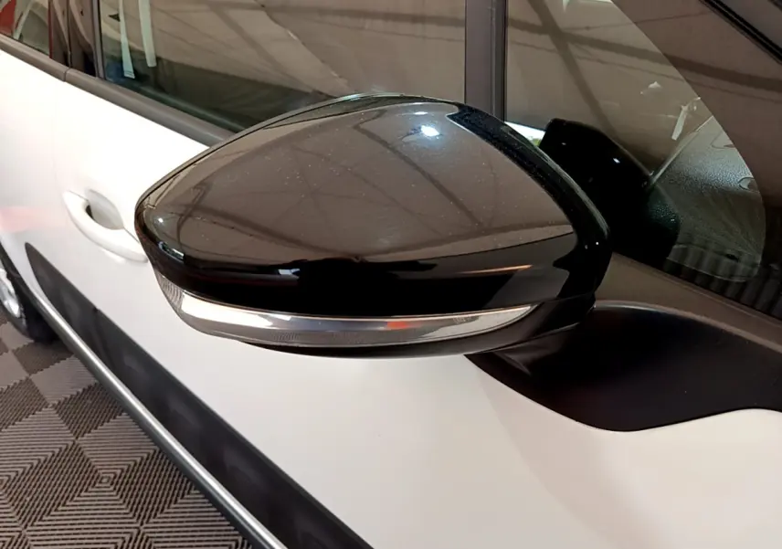 Rétroviseur noir avec clignotant intégré côté droit sur une Citroën C3 blanche vue de profil rapproché.