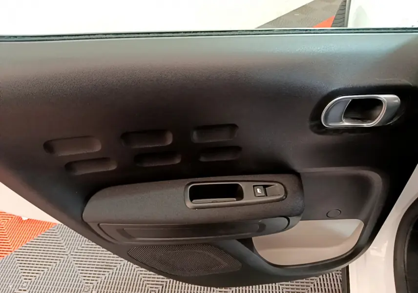 Porte intérieure côté conducteur noire avec poignée intégrée et bouton de verrouillage sur Citroën C3 blanc 2019.