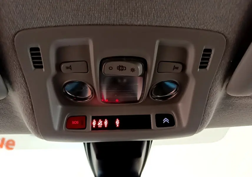 Vue en plongée du plafonnier gris clair de la Citroën C3 avec boutons SOS et éclairage intérieur allumé.