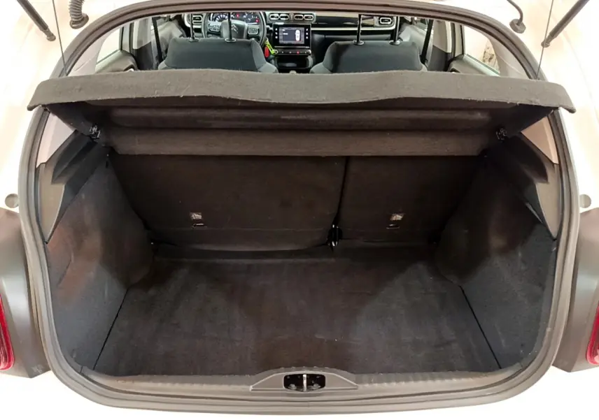Coffre ouvert d'une Citroën C3 blanche vue de l'arrière, montrant l'espace de chargement et l'intérieur noir.