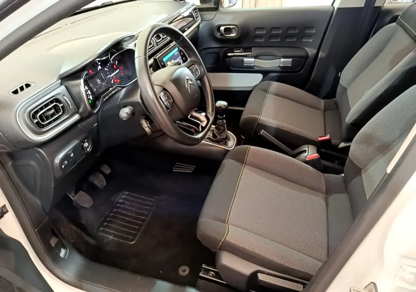 Intérieur avant droit d'une Citroën C3 blanche 2019, sièges gris, volant cuir et tableau de bord avec écran tactile.