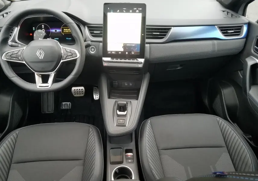 Vue intérieure avant du Renault Captur 2025, tableau de bord moderne avec écran tactile vertical et sièges noirs.