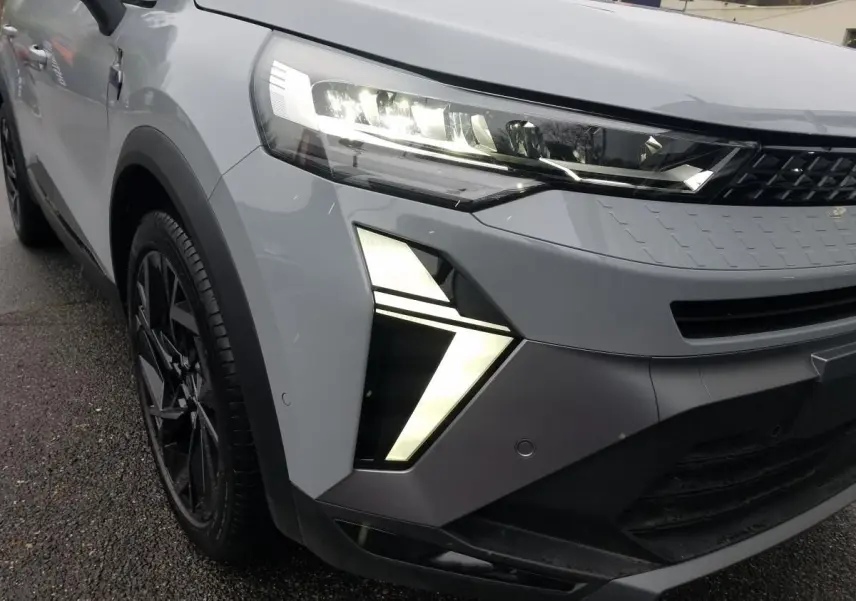 Gros plan sur l'avant gauche du Renault Captur gris Rafale 2025 avec feux LED distinctifs allumés.