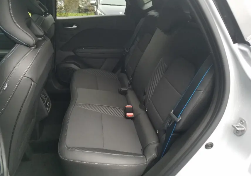 Vue côté droit des sièges arrière noirs avec surpiqûres blanches et ceinture de sécurité bleue du Renault Captur gris Rafale 2025.