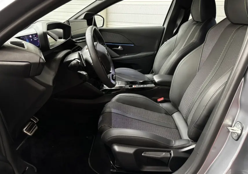 Intérieur avant droit de la Peugeot 208 Hybrid gris clair, sièges cuir et tableau de bord avec écran tactile.