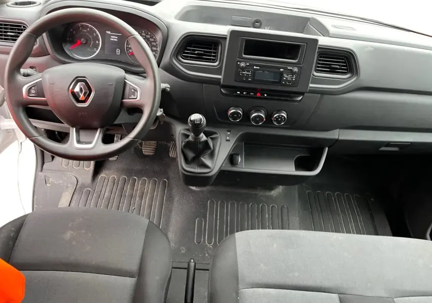 Vue intérieure du tableau de bord et volant noir du Renault Master Châssis Cabine blanc, avec levier de vitesses manuel et sièges tissus noirs.