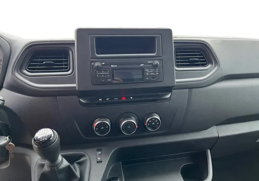 Vue intérieure centrée sur la console centrale du Renault Master Châssis Cabine 2023 avec boîte manuelle et commandes climatisation.
