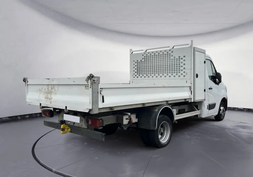 Vue 3/4 arrière droite d’un Renault Master blanc avec benne et coffre, roues jumelées et hayon arrière sali.