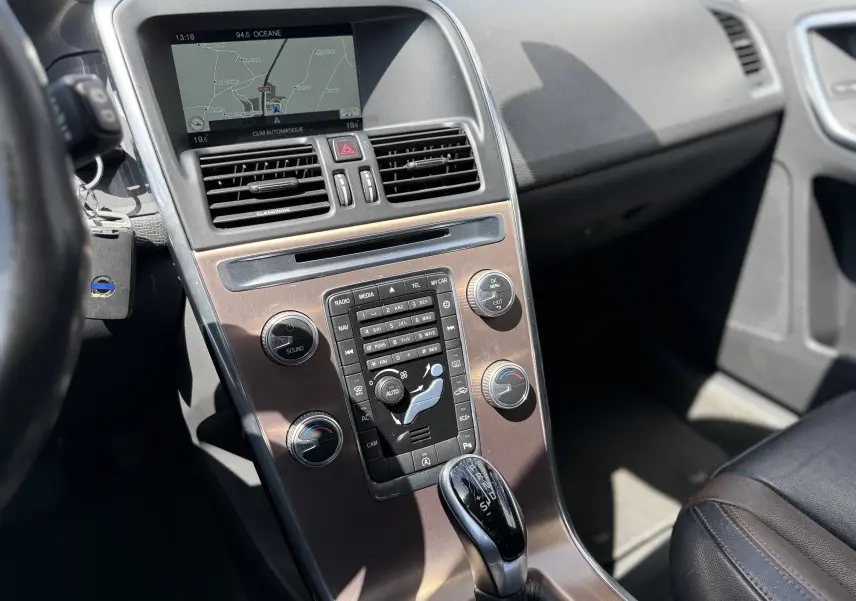 Vue rapprochée de la console centrale gris foncé du Volvo XC60 2016, avec écran GPS et commande de boîte automatique.